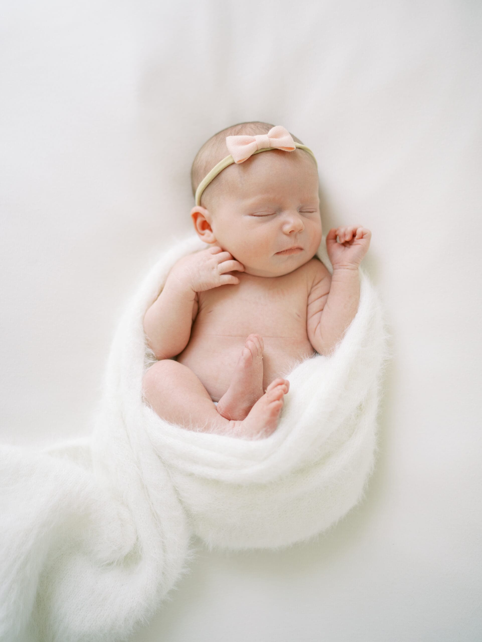 Lifestyle photographer swaddling newborn wrap during relaxed photo session in Plano