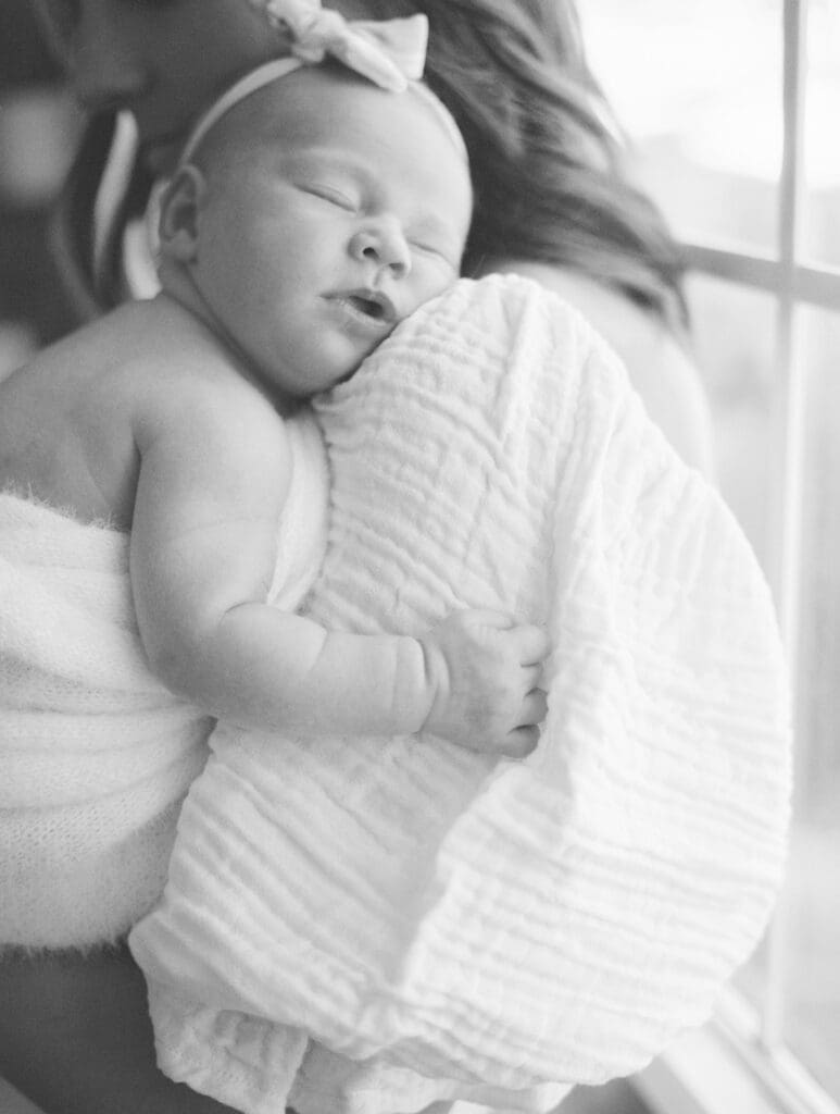 Mom snuggled up with her newborn daughter during an at home newborn session in Argyle, Texas.