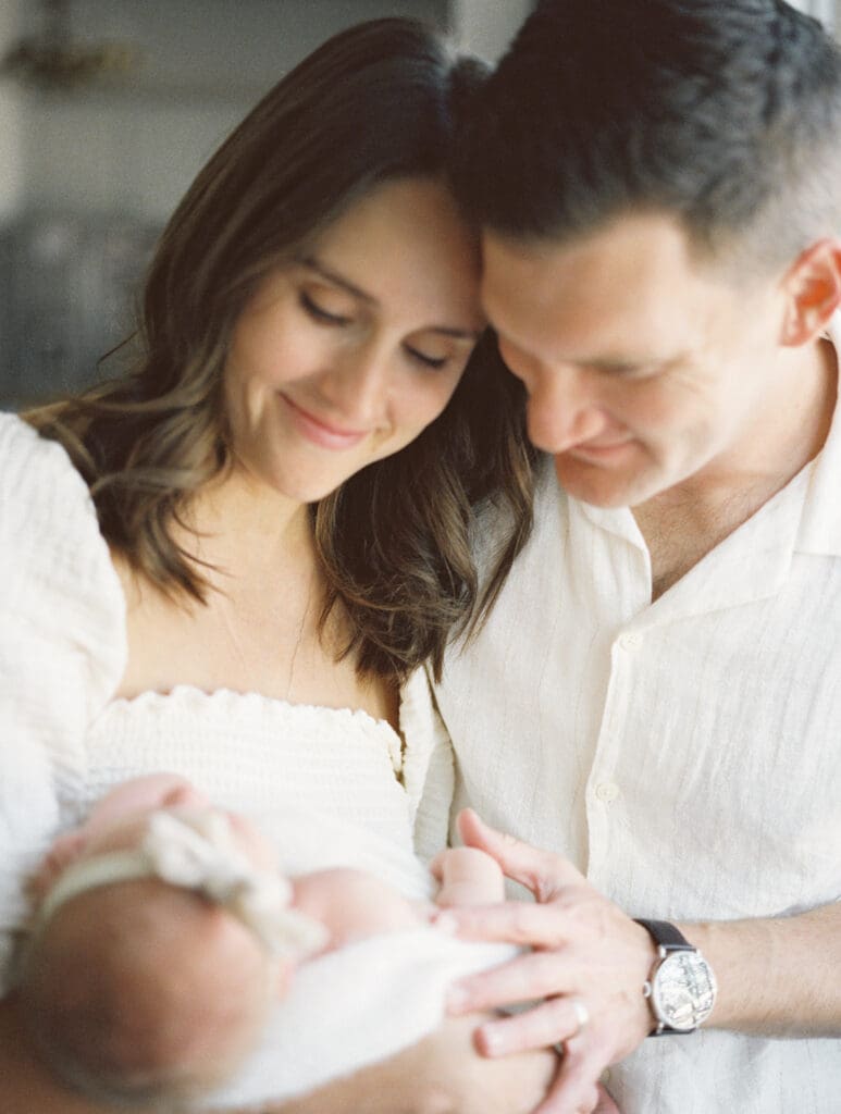 Parents admiring their newborn daughter during an in home family session in Fort Worth, Texas.