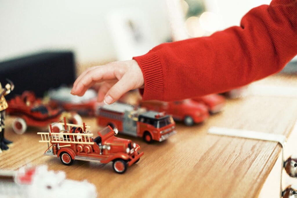 Little kid reaching for her Dad's childhoos Christmas train collection