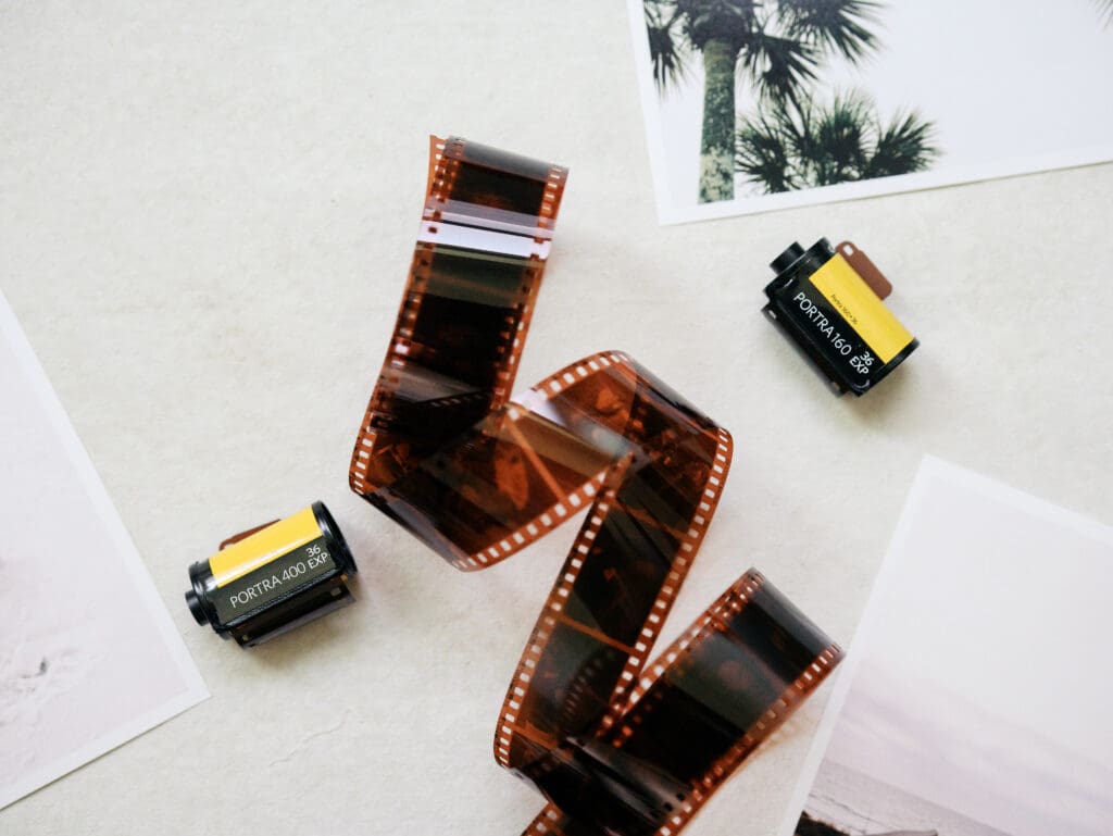 A photo of a film strip and two rolls of kodak 35mm film