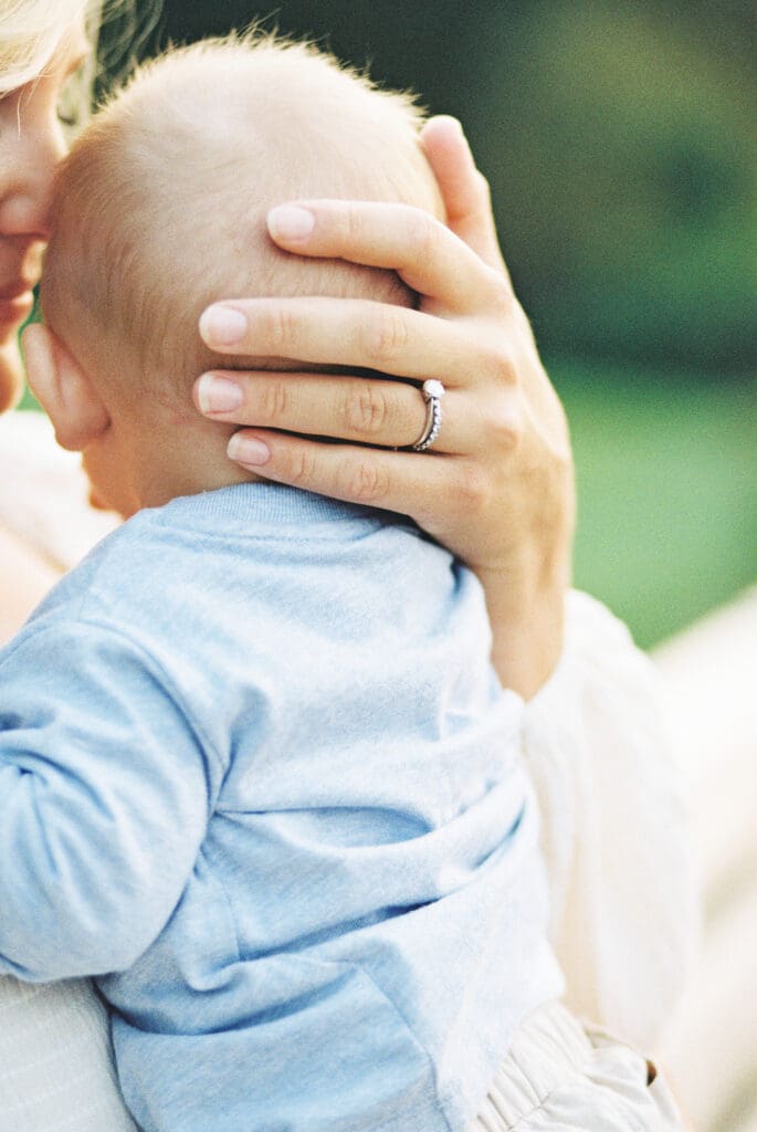 Mom embracing her newborn son during an outdoor family session taken by Kayla Mari Photography.